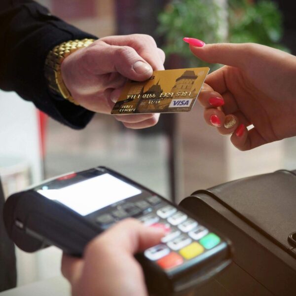 Customer handing a gold credit card to a woman, who is holding a point of sale credit card reader.