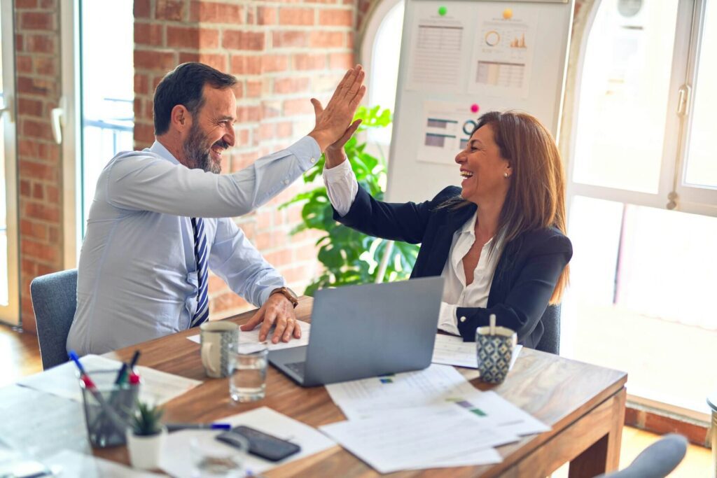 Two workers high-fiving while discussing KPI incentive schemes