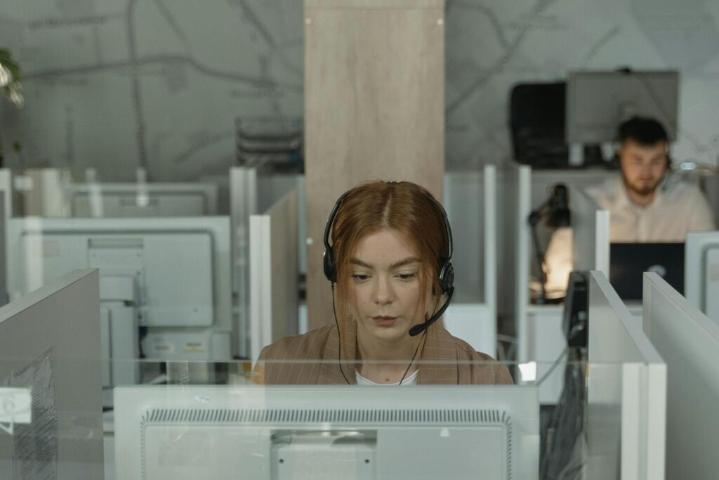 Woman sitting at a desk in front of a computer and wearing a headset.