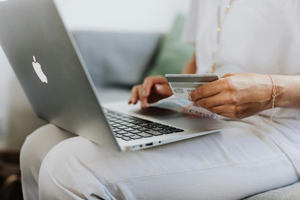 Lap of a person holding payment card and using laptop