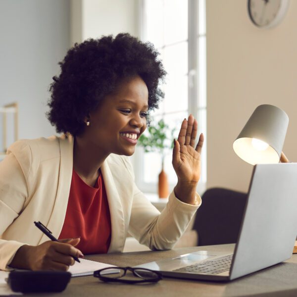 A virtual team meeting with smiling, diverse participants in a modern remote workplace setting, emphasizing human connection in hybrid work