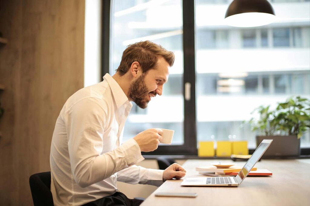 A happy business professional at his desk looking over rebate reporting information