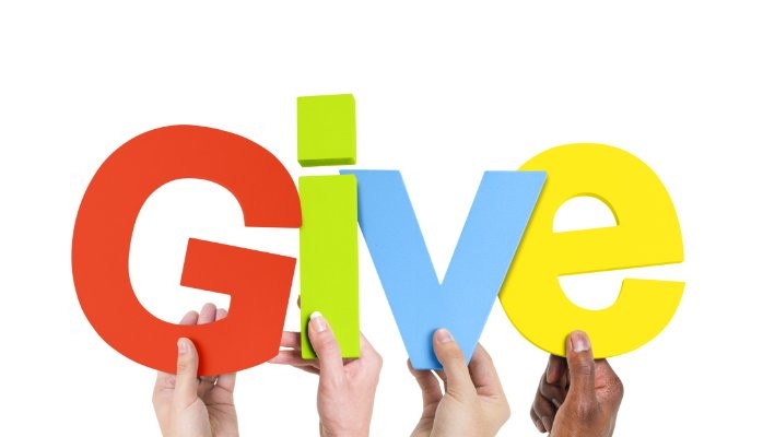 Hands holding up letters that spell the word give