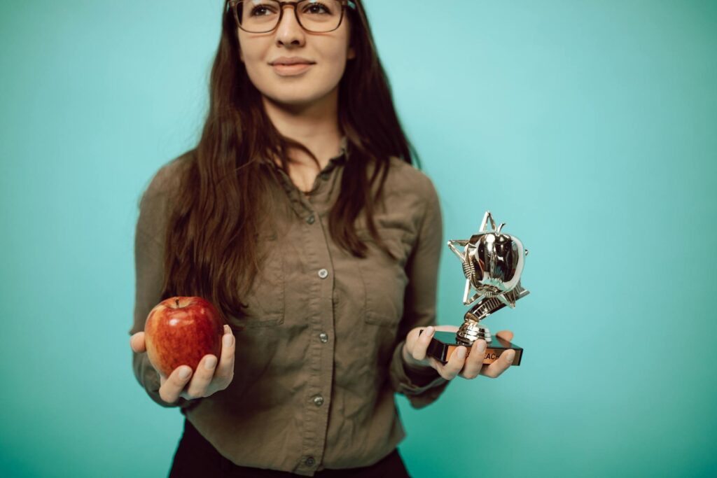 A person holding an apple in one hand and an award in the other hand
